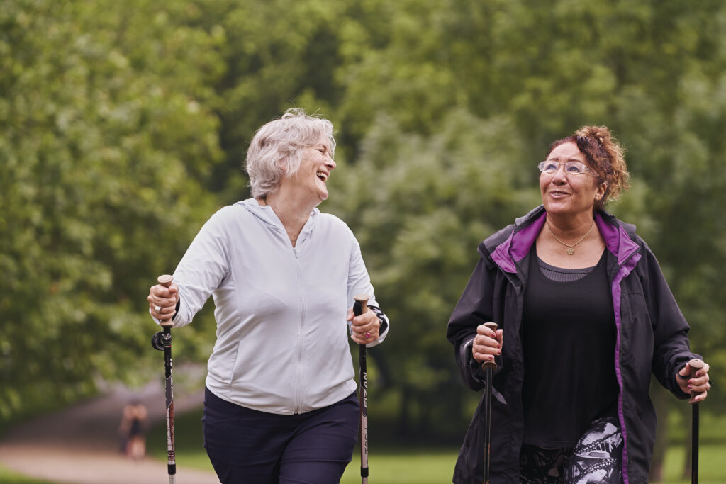 Two older women outdoors hiking with walking sticks