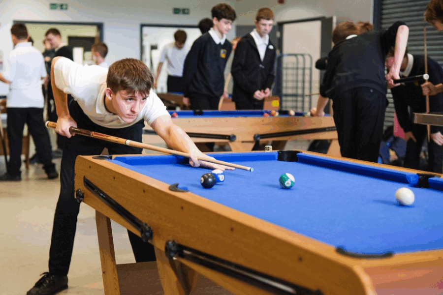 Young boy at school playing pool