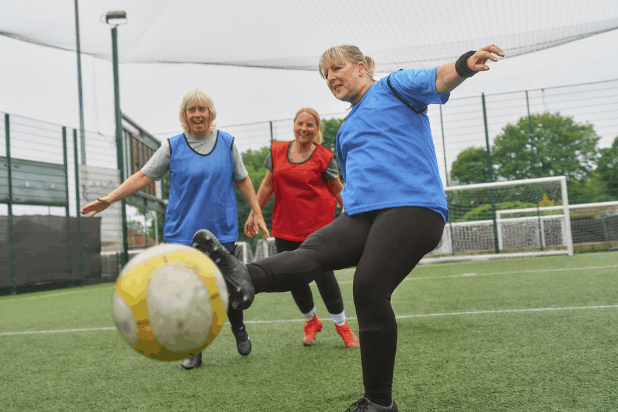 3 middle aged women playing football